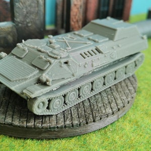 Può includere: Un modello di veicolo militare cingolato in plastica grigia. Il modello è dettagliato con un portello rialzato e una serie di piccole ruote.