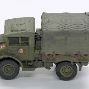 Puede incluir: Un modelo de camión militar verde con una lona y banderas canadienses en el lateral. El camión tiene un aspecto desgastado y está hecho de plástico.