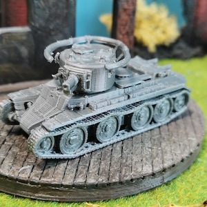 以下が含まれることがあります： 回転する砲塔を持つ戦車のグレーの精密なモデル。戦車は木製の台座の上にあり、緑の草に囲まれています。