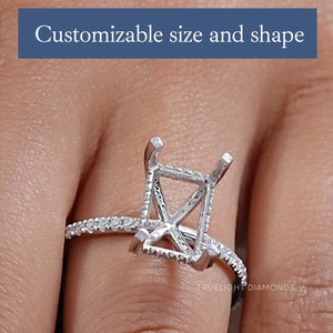 Puede incluir: Un anillo de plata con un engaste cuadrado para una piedra central. El anillo está engastado con pequeños diamantes alrededor de la banda. El texto "TRUE LIGHT DIAMONDS" es visible en la banda.