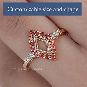 May include: A gold ring with a diamond-shaped setting featuring a halo of red gemstones. The ring is customizable in size and shape. "TRUEUGHT DIAMONDS" is printed on the band.