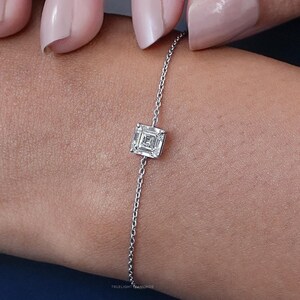May include: A delicate silver chain bracelet with a single square-shaped diamond pendant.