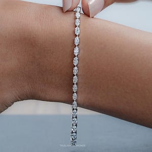 Op de afbeelding: Een sierlijk armband met een reeks marquise-geslepen diamanten. De diamanten zijn dicht op elkaar geplaatst, waardoor een doorlopende lijn van schittering ontstaat. De armband wordt getoond op een pols, wat het elegante ontwerp benadrukt.