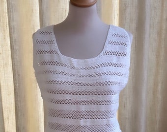 May include: White crochet sleeveless top with a scoop neck. The top is made of a delicate, open-weave fabric.