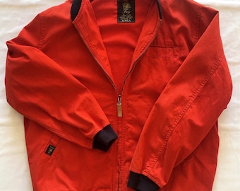 May include: A red bomber jacket with black ribbed trim around the collar, cuffs, and hem. The jacket has a zipper closure and a small pocket on the left chest. The label on the jacket reads "Roy, Made in Italy, EMA."