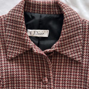 Può includere: Una giacca di tweed rosso e bianco con fodera nera e un'etichetta che recita "l'Elisir" made in Italy.