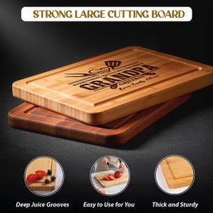 May include: Two wooden cutting boards, one light-colored and one dark, are stacked. The top board has the text "STRONG LARGE CUTTING BOARD" and "GRANDPA GRILLS IT" engraved. The bottom board is a darker wood. The image also shows details of the boards, including deep juice grooves.