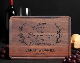 May include: A rectangular wooden cutting board with a dark brown finish. The board is engraved with the words "New Home, New Beginnings, New Memories" and the names "Sarah & Daniel" with the year "Est. 2025".