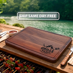 Puede incluir: Tabla de cortar rectangular de madera marr&oacute;n oscuro. La tabla tiene una ranura tallada alrededor del borde y un gr&aacute;fico negro que dice "Grills Jonathan". Una parrilla con brochetas de verduras est&aacute; en primer plano.