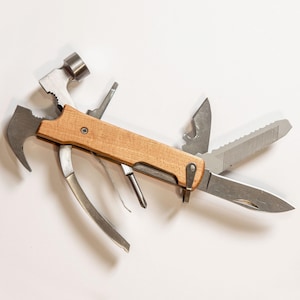 K&ouml;nnte beinhalten: Ein Multitool mit Holzgriff und verschiedenen Metallaufs&auml;tzen, darunter ein Hammer, Messer, S&auml;ge und Zange. Das Werkzeug ist f&uuml;r vielf&auml;ltige Zwecke konzipiert und wird vor wei&szlig;em Hintergrund gezeigt.