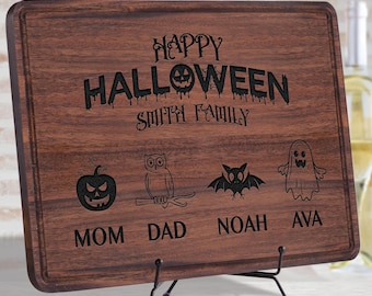 Könnte beinhalten: Ein rechteckiges, dunkelbraunes Holzschneidebrett mit einer Lasergravur, die Happy Halloween Smith Family liest. Unter dem Text befinden sich vier Symbole: ein Kürbis, eine Eule, eine Fledermaus und ein Geist, mit den Namen Mom, Dad, Noah und Ava.