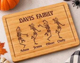 Könnte beinhalten: Ein rechteckiges Schneidebrett aus Bambus mit einer Lasergravur von vier tanzenden Skeletten mit Kürbisköpfen. Der Text "DAVIS FAMILY" steht oben, darunter die Namen "Adam", "Jenna", "Oliver" und "Cindy" unter jedem der Skelette.