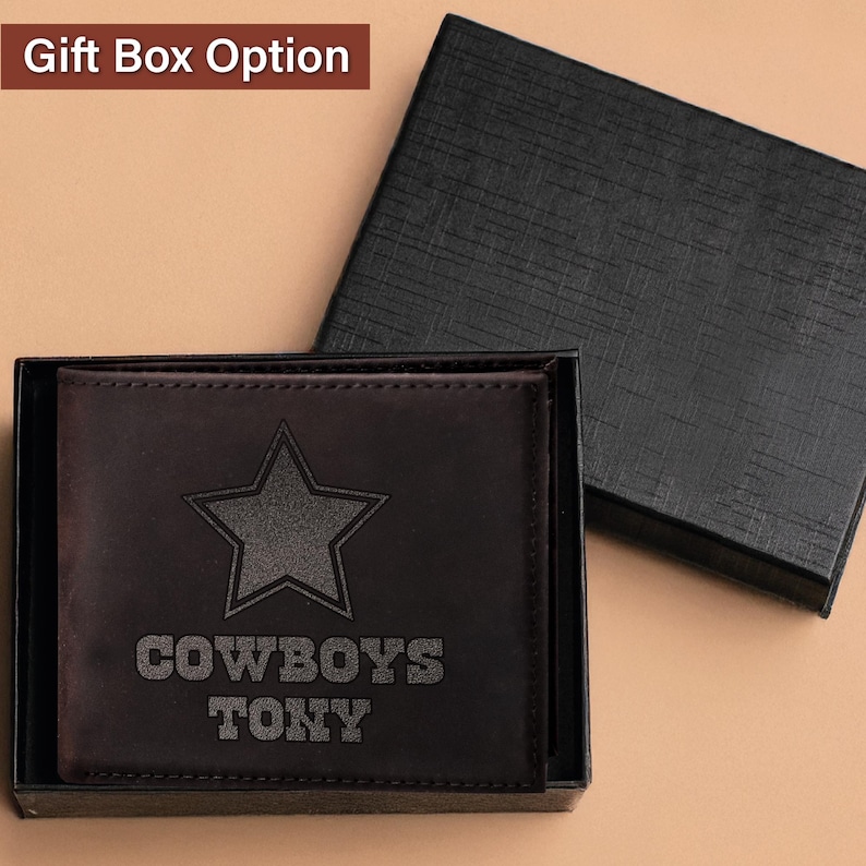 May include: A brown leather wallet with a black star and the words "COWBOYS TONY" engraved on the front. The wallet is in a black gift box.