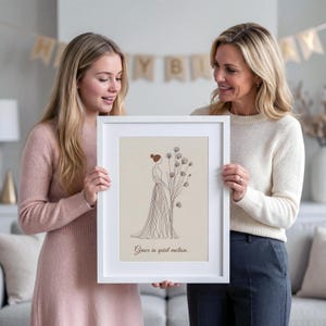 Puede incluir: Una impresión artística enmarcada con un dibujo lineal de una mujer con un vestido largo y flores. La obra de arte es en tonos marrones y beige, con el texto "Grace in quiet motion." El marco es blanco.