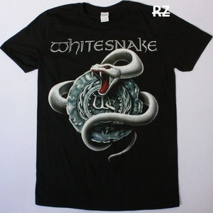 Può includere: Maglietta nera con un serpente bianco avvolto attorno a un sigillo argentato con il testo "Whitesnake" sopra il serpente.