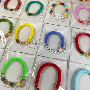 May include: Assortment of colorful beaded bracelets with personalized names and the phrase "Do all things with love". The bracelets are displayed on white cards with the length of each bracelet listed in inches.