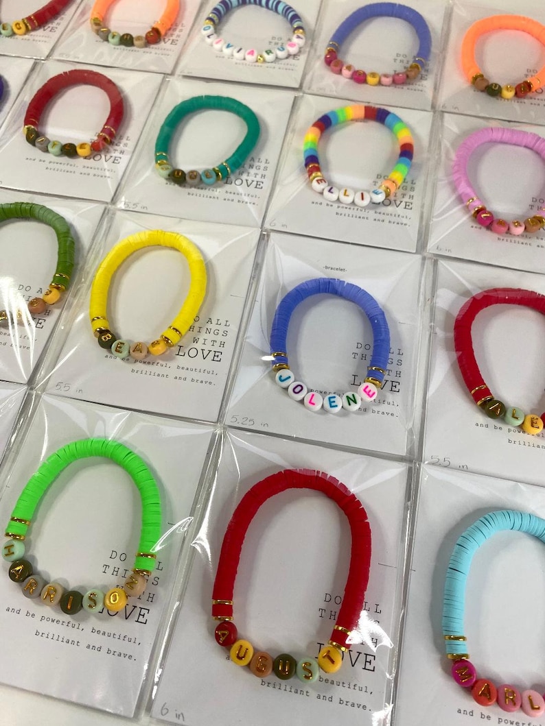 May include: Assortment of colorful beaded bracelets with personalized names and the phrase "Do all things with love". The bracelets are displayed on white cards with the length of each bracelet listed in inches.