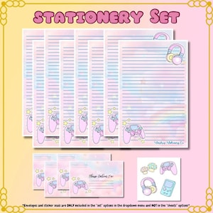 May include: A stationery set featuring lined paper, envelopes, and stickers with a pastel rainbow and gaming theme. The set includes illustrations of game controllers, headphones, and stars. The text "STATIONERY SET" is displayed at the top.