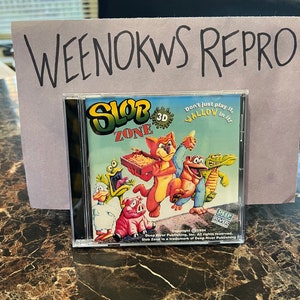 May include: A CD case for the game "Slob Zone 3D" featuring a cartoon cat, pig, frog, and alligator. The text on the case reads "Don't just play it, wallow in it!" and "Copyright © 1994 Deep River Publishing, Inc. All rights reserved. Slob Zone is a trademark of Deep River Publishing."