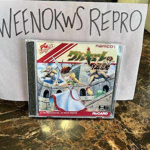 Puede incluir: Un cartucho de juego PC Engine HuCard para el juego 'Crystalis' de Namco. El cartucho es rojo, blanco y dorado con texto japonés y una imagen de un personaje femenino con una espada.