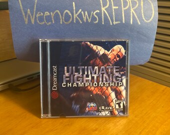 May include: A Dreamcast video game case with a blue and white background. The game is called "Ultimate Fighting Championship" and features a photo of two fighters in a cage. The game is rated T for Teen by the ESRB.