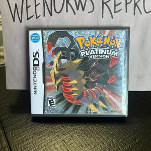 May include: A Nintendo DS game cartridge for Pokemon Platinum Version. The game features a black and red Pokemon on a silver background. The game is rated E for Everyone by the ESRB.