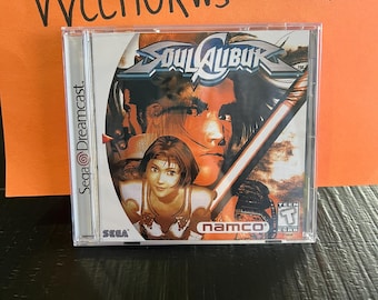 May include: A Sega Dreamcast game case for Soulcalibur. The case is orange and black with a picture of a character holding a sword. The game is rated T for Teen by the ESRB.