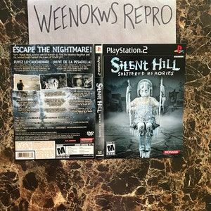 May include: A PlayStation 2 video game case for Silent Hill: Shattered Memories. The front cover features a girl in a white dress standing in a snowy street. The back cover has a description of the game and a mature rating.