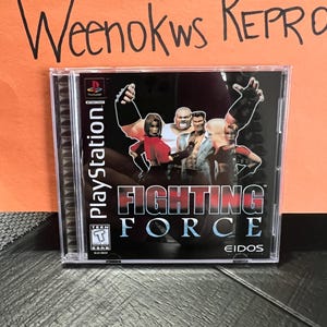 May include: A PlayStation game case with a black background and the title "Fighting Force" in white text. The game is rated "Teen" by the ESRB. The case is in a plastic sleeve.