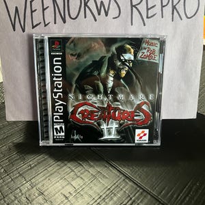 May include: A PlayStation game case for Nightmare Creatures II, a mature-rated game with a red and black cover featuring a character with a blindfold and the text "Nightmare Creatures II". The game features music by Rob Zombie.