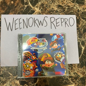 Op de afbeelding: Een transparante plastic hoes met een CD erin. De CD-hoes heeft een kleurrijke illustratie van een cartoonfiguur die een paraplu vasthoudt. De tekst op de CD-hoes luidt "Parasol Stars: The Story of Bubble Bobble III".