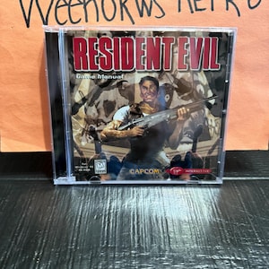 May include: A Resident Evil game manual in a clear plastic jewel case. The cover features a character holding a shotgun with the text Resident Evil, Game Manual, Capcom, and Virgin Interactive. The ESRB M rating for Windows 95 is visible.
