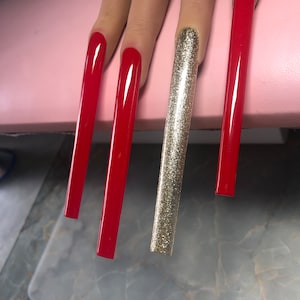 May include: Four long, artificial fingernails. Three are painted red and one is covered in gold glitter.