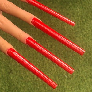Pode incluir: Quatro unhas compridas de cor vermelha brilhante com um acabamento brilhante.