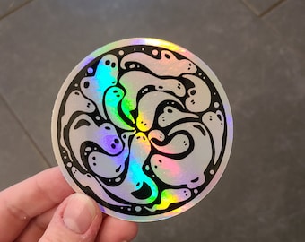May include: A round, iridescent sticker with a black outline. The sticker features a design of multiple white ghosts swirling together.