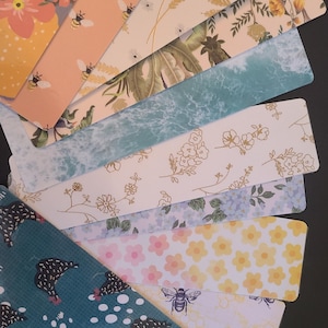 May include: A set of ten colorful bookmarks with various patterns. The patterns include lemons, bees, flowers, and a chicken design. The bookmarks are all rectangular and have a white background.