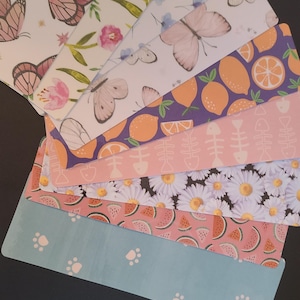 May include: A set of eight colorful patterned gift tags featuring various designs, including butterflies, lemons, watermelon, daisies, and paw prints.