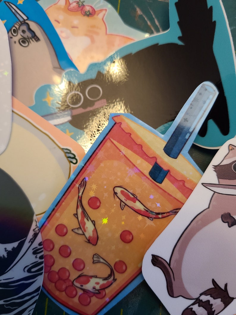 K&ouml;nnte beinhalten: Ein Aufkleber mit einem Bubble Tea mit roten und orangen Boba-Perlen, zwei wei&szlig;en und orangen Fischen und einem blauen und wei&szlig;en Strohhalm. Der Aufkleber hat eine glitzernde Oberfl&auml;che.