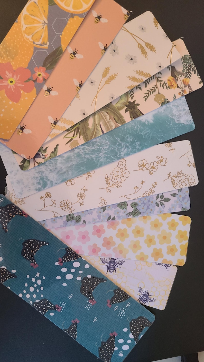 May include: A set of ten colorful bookmarks with various patterns. The patterns include lemons, bees, flowers, and a chicken design. The bookmarks are all rectangular and have a white background.
