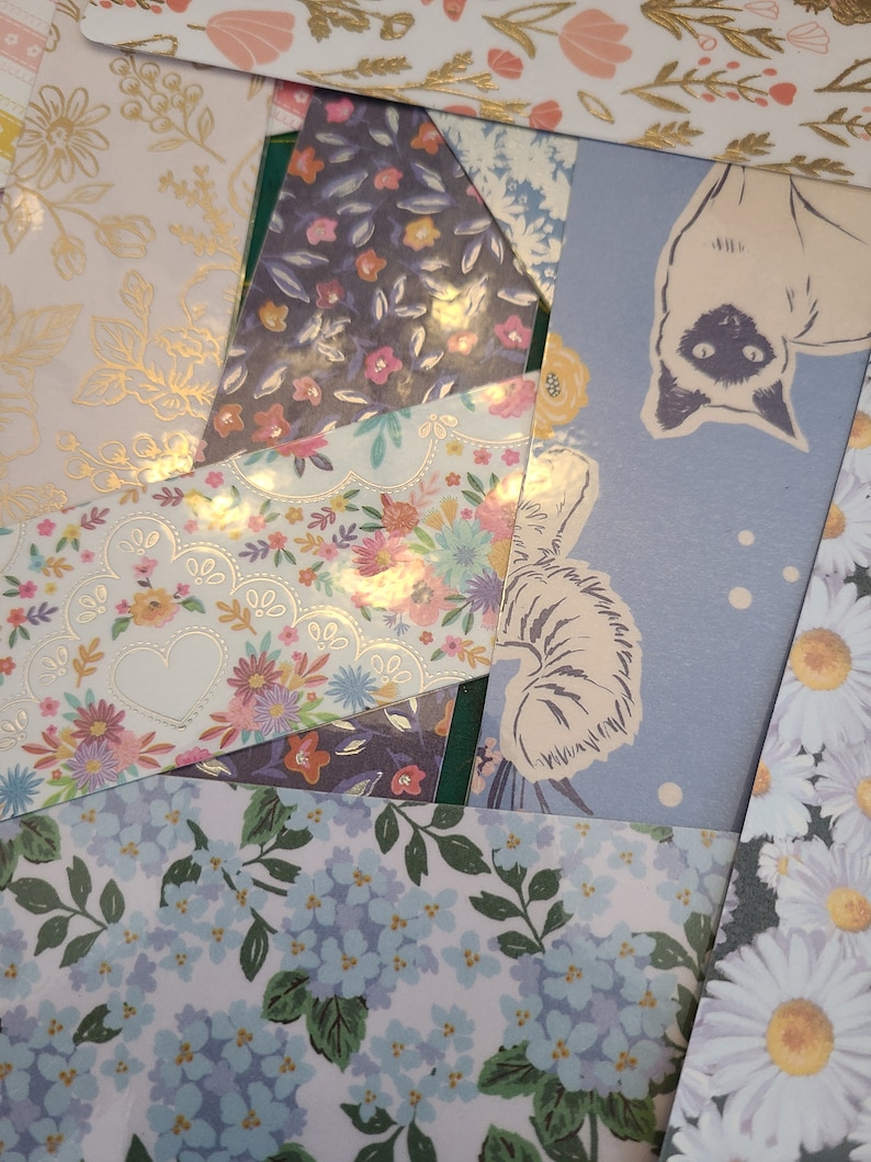 May include: A collection of patterned paper scraps with floral and animal designs. The papers are in various shades of blue, pink, and white.