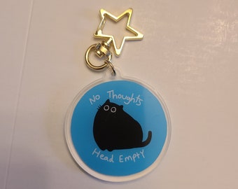 May include: A round, blue and white keychain with a black cat illustration. The text "No Thoughts Head Empty" is written around the cat.