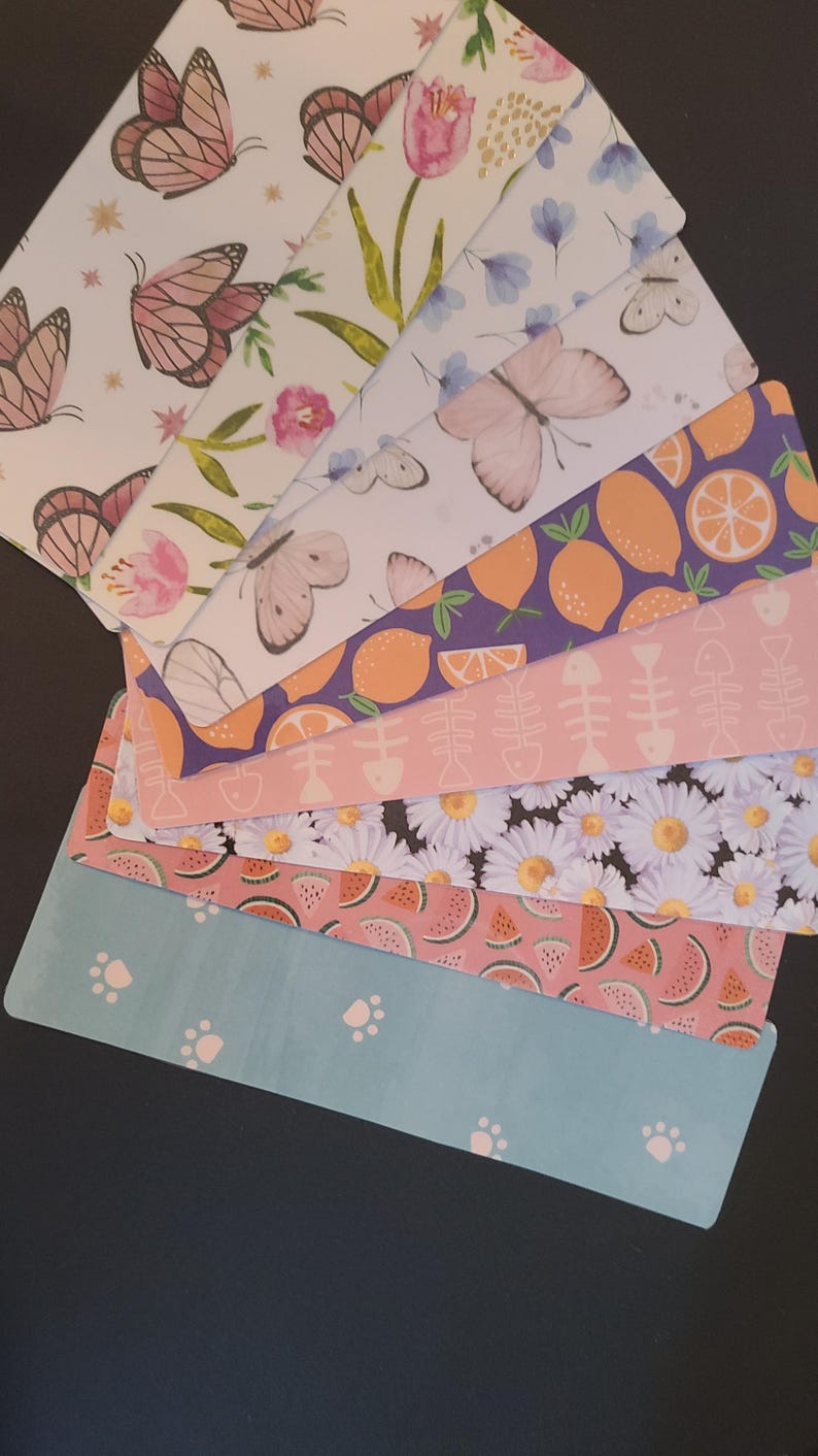 May include: A set of eight colorful patterned gift tags featuring various designs, including butterflies, lemons, watermelon, daisies, and paw prints.