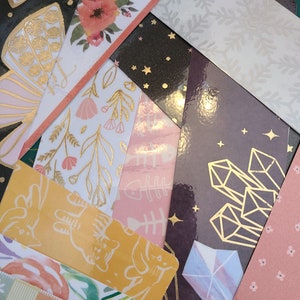 May include: A collection of colorful bookmarks with various designs, including floral patterns, geometric shapes, and animal illustrations. The bookmarks are made of paper and have a glossy finish.