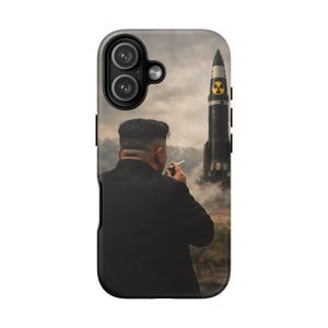 May include: Phone case featuring a man smoking a cigarette, with a missile in the background. The image has a cloudy, overcast sky and a landscape with a mountain range. The phone case is black.