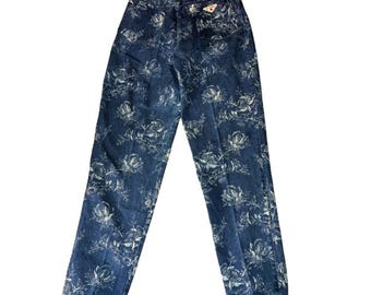 May include: Dark wash denim jeans with a white floral pattern. The jeans have a high waist and a straight leg cut. The back features two pockets and a small logo patch. The overall style is vintage.