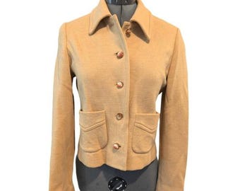 May include: A tan jacket with a collared neckline, four gold-colored buttons, and two front pockets. The jacket is displayed on a mannequin. The jacket is a neutral color and has long sleeves.