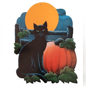 May include: A Halloween-themed decoration featuring a black cat, a large orange pumpkin, and a full moon. The cat is sitting in front of the pumpkin, with a wooden fence and foliage in the background. The moon is a bright orange circle.