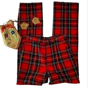 May include: Red plaid pants with a matching pair of shorts and a decorative bag. The pants and shorts feature a classic red, black, and white plaid pattern. The bag is beige with floral embroidery and a drawstring closure.