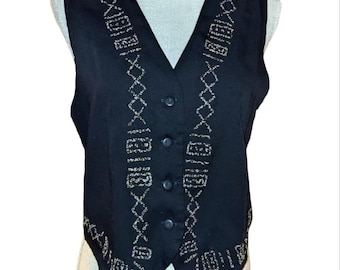 May include: Black vest with a V-neck and button closure. The vest features an embroidered design in a light beige color. The embroidery includes geometric and linear patterns. The vest is sleeveless and appears to be made of a woven fabric.