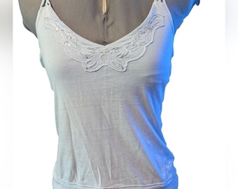 May include: A light blue tank top with a V-neckline and delicate beaded embellishments. The top features thin, braided straps and a fitted silhouette. The neckline is adorned with a scalloped lace design, embellished with small, shiny beads.